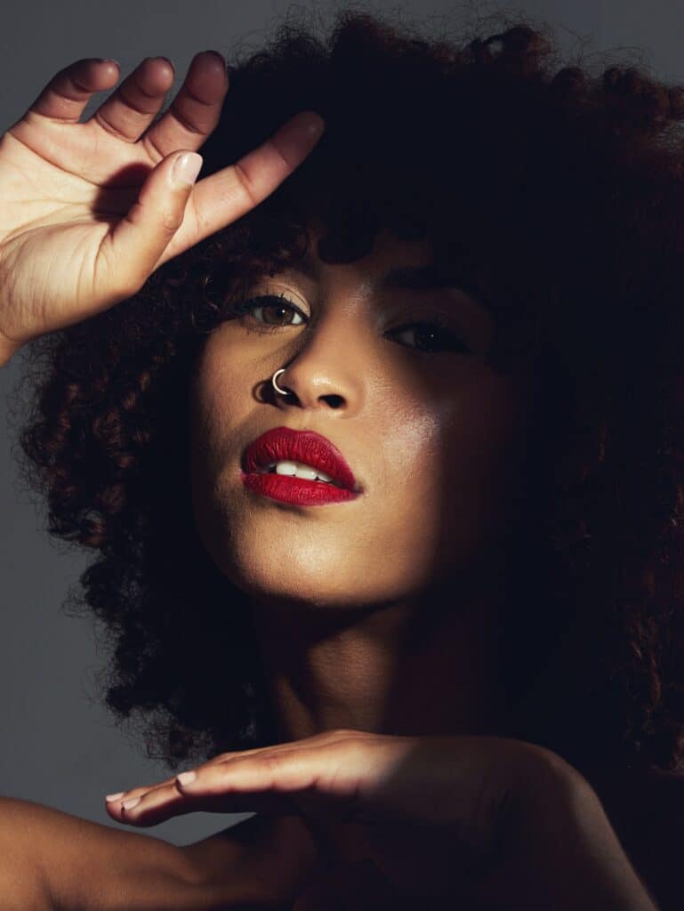 Red lipstick, shadow and makeup on black woman with beauty, afro or natural hair in studio. Face of