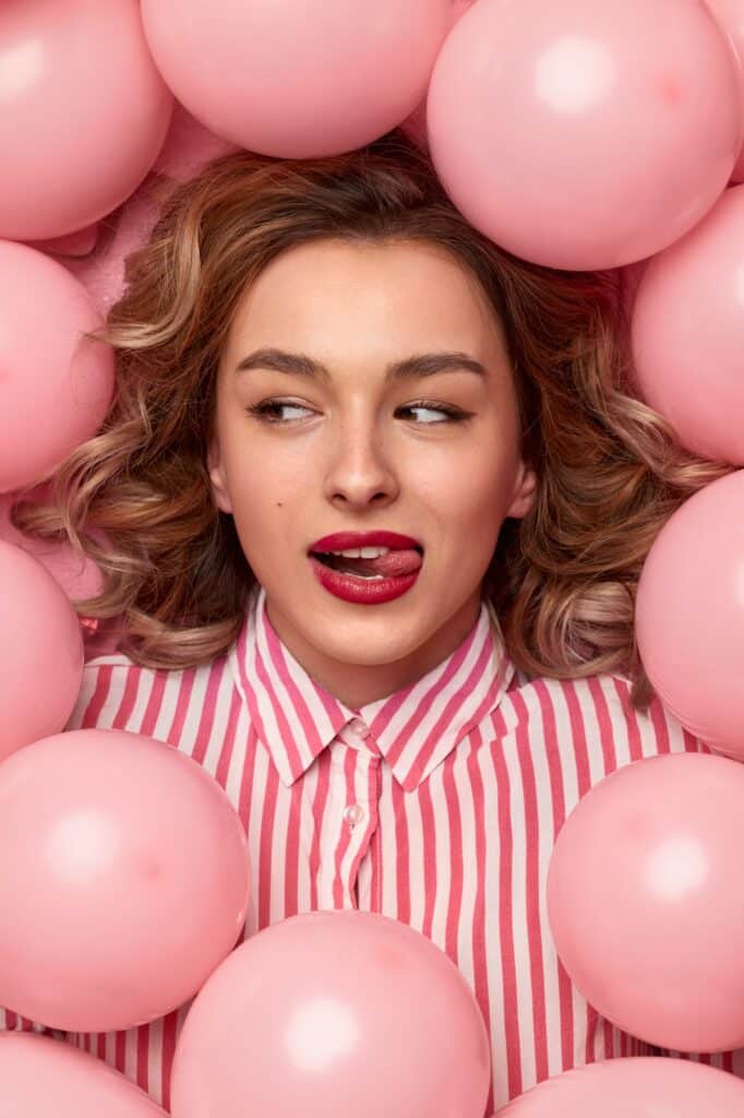 Beautiful woman in balloons licking lips